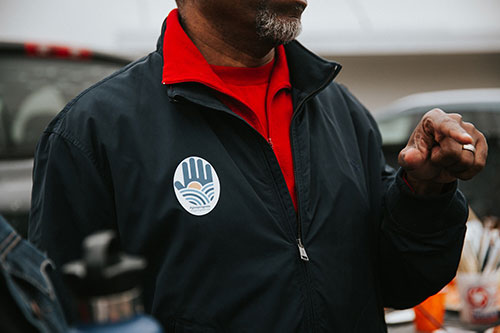 A giving wall logo sticker on a person's jacket at the Giving Wall mural at Perch